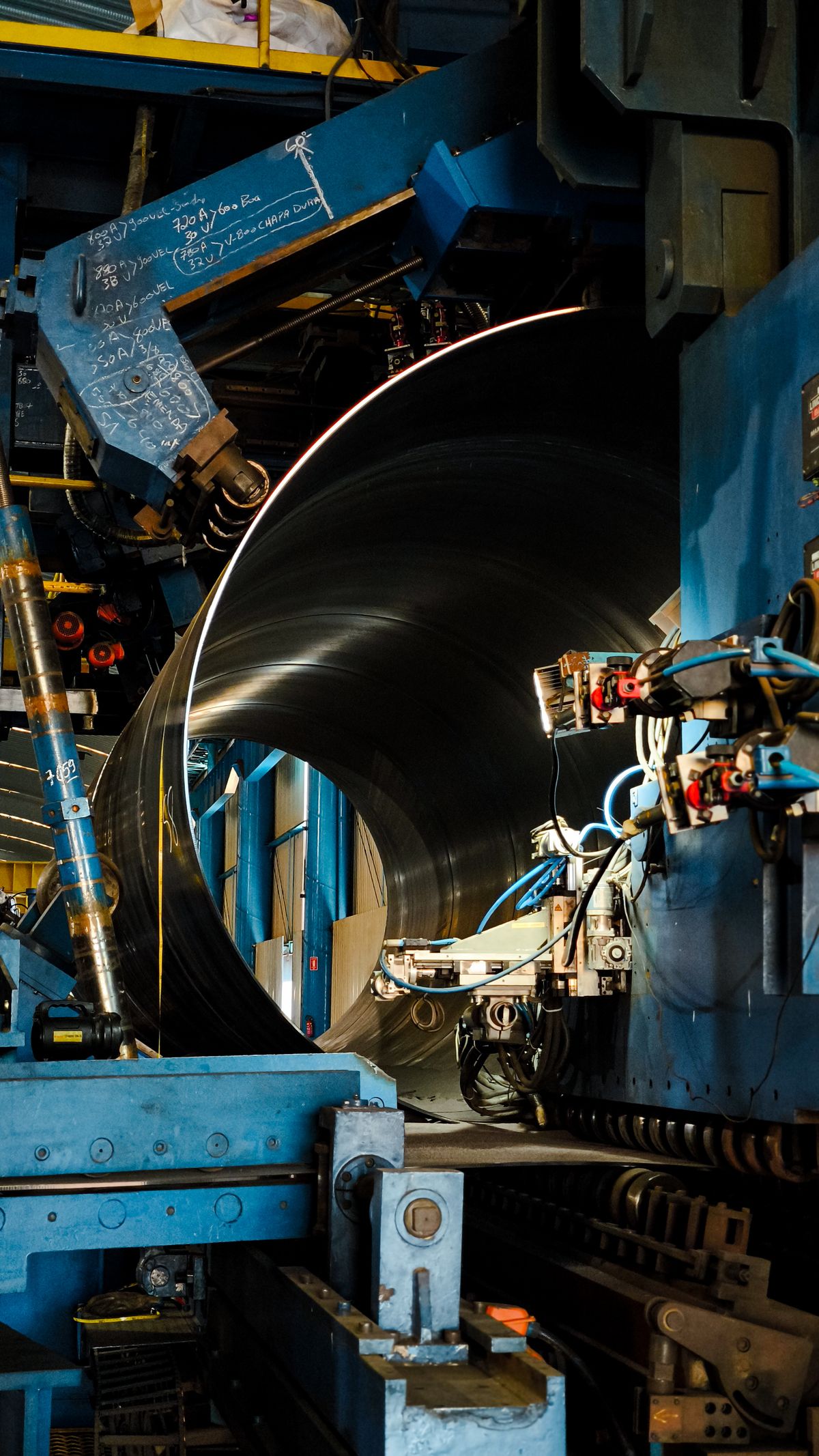Large cylindrical steel component being processed by heavy engineering machinery